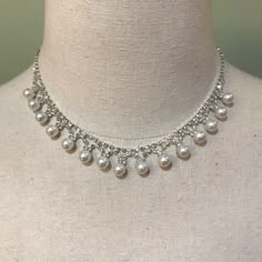 a white necklace with pearls on a mannequin