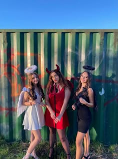 three women dressed up in costumes standing next to a wall