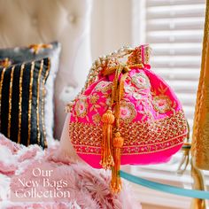 a pink purse sitting on top of a bed next to pillows and a window with gold trim