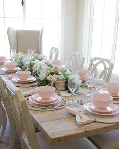 a dining room table set with pink dishes and place settings for six people to eat