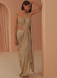 Glam Vibes in this gold gleam pleated drape saree teamed with a corset encrusted with stone work and zardosi in gold hues. This ensemble is a ready to wear saree for your ease ! Blouse can have straps added for ease. Composition: Saree - Lycra Net, Blouse- Net , Lining-Butter Crepe All products can be customised for sleeves, length of blouse and neck design Delivery : 4-6 weeks as the product is hand crafted. Check Size Guide or choose MySize for free customisation (All Sizes above XL can be made at 15% additional cost) For more information and sizes please contact fabiliciousfashion@gmail.com or visit our Copenhagen studio. About the Designer : Parul Gandhi is a name that exudes opulence and elegance. The design philosophy of Parul Gandhi Label revolves around color balance and placement Festive Gold Embellished Pre-draped Saree, Gold Floor-length Pre-draped Saree With Cutdana, Gold Pre-draped Saree For Party, Fitted Gold Pre-draped Saree For Festive Occasions, Gold Pre-draped Saree With Cutdana For Party, Festive Draped Glamorous Blouse Piece, Festive Glamorous Draped Blouse Piece, Glamorous Draped Saree For Wedding, Glamorous Draped Wedding Saree