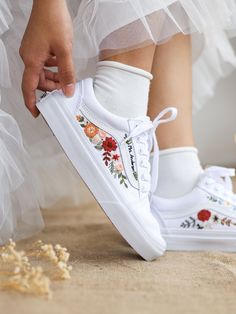 a person wearing white shoes with flowers on them