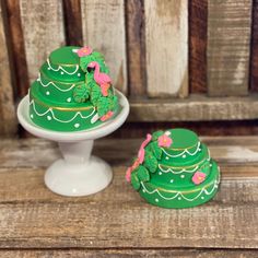 two green cakes sitting on top of a white cake platter next to each other