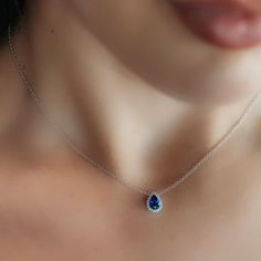 a woman wearing a necklace with an oval blue stone