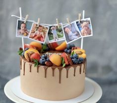 a cake decorated with photos and fruit on a plate