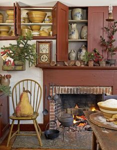 an old fashioned fireplace with pots and pans on the mantel, next to a wooden rocking chair