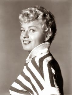 an old photo of a woman wearing a striped sweater and posing for the camera with her hands on her hips