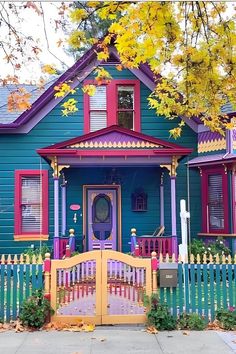 a blue house with red shutters and a yellow picket fence in front of it