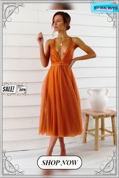 a woman in an orange dress posing for the camera