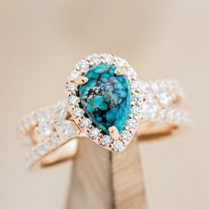 a ring with a blue stone surrounded by white and brown diamonds on top of a piece of wood