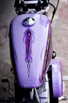 a purple motorcycle with an intricate design on the front fender and side view mirror, parked in a parking lot