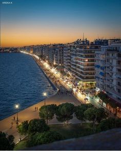 the city is lit up at night by the water