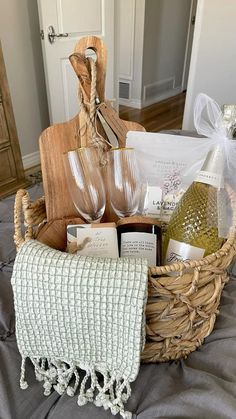 a wicker basket filled with wine glasses and other items on top of a bed