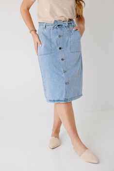 Create an instant feminine look wearing the 'Cassidy' Skirt! Featuring a button-front design and tie waist, this denim midi skirt makes a perfect choice for both casual or formal occasions. The soft, lightweight denim in a regular fit offers comfort, while the pull-on style allows easy wear. Pair the 'Cassidy' with a black tee and sneakers for a fun day in the city or running errands in town! 75% Cotton 25% Polyester Hand Wash Cold Do Not Bleach Hang to Dry Low Iron if Needed Model Height 5'7" | Denim Midi Skirt, Light Wash Denim, Feminine Look, Front Design, Formal Occasion, Easy Wear, Modest Outfits, Stretch Denim, Black Tee