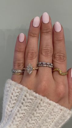 a woman's hand with three different rings on her fingers and one is wearing a white sweater