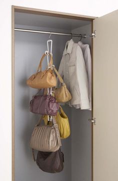 several purses hanging from hooks in a closet