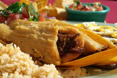 mexican food on a plate with rice, beans and tortilla shells in the background