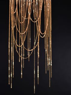 a chandelier hanging from the ceiling with gold chains on it's sides