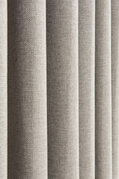 a close up view of a curtain with vertical blinds in beige fabric, which is slightly open