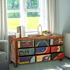 a colorful chest of drawers in front of a window