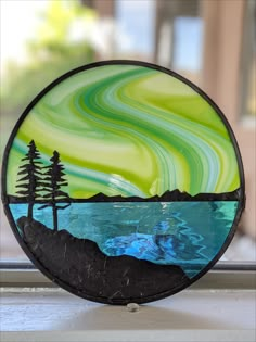 a glass plate sitting on top of a window sill next to a lake and trees