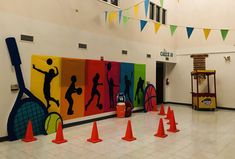 there are many colorful paintings on the wall in this school gym area that is decorated with orange cones and tennis rackets