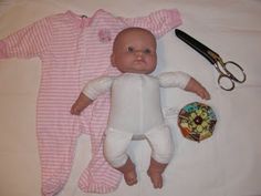 a baby doll laying on top of a bed next to a pair of scissors