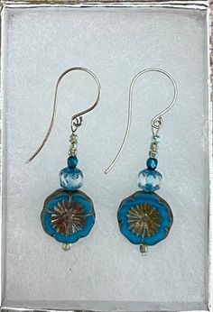 a pair of dangle earrings with blue and brown glass beadwork on them