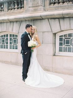 a bride and groom standing in front of a building