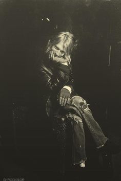 a black and white photo of a woman sitting in a chair with her hand on her face