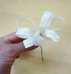 someone is holding a piece of white fabric with a bow on it's end