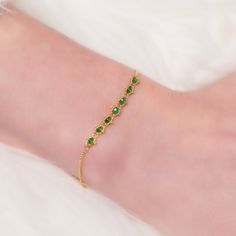 Emerald Textile Station Bracelet on a wrist diagonal view Formal Gold-plated Diamond Bracelet With Adjustable Chain, Yellow Gold Bracelets For May Birthstone, Formal Fine Jewelry Delicate Chain Bracelet, Yellow Gold Emerald Bracelet For Formal Occasions, Formal Yellow Gold Bracelets For May Birthstone, Formal Yellow Gold Bracelet With May Birthstone, Gold Gemstone Chain Bracelet In 14k Gold, Flexible Yellow Gold Chain Bracelet, Elegant Gold Diamond Bracelet With Box Chain