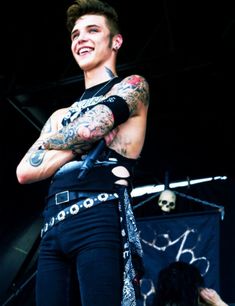 a man with tattoos on his arms and chest standing in front of a black background