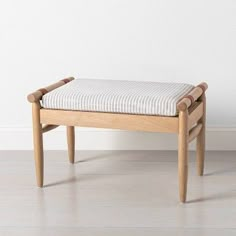 a wooden bench sitting on top of a hard wood floor next to a white wall