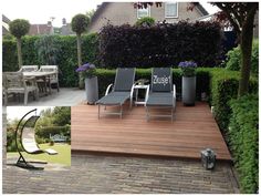 a wooden deck surrounded by chairs and plants