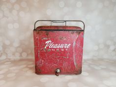 an old red metal box sitting on top of a table