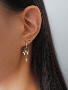 Fun and femme, these silver hoop earrings dipped in rhodium feature a bold asymmetric design and playful mismatched charms designed to elevate every stack. Cute Sterling Silver Earrings, Silver Earrings Hoop, Sliver Earing Ideas, Cute Jewelry Silver, Silver Earrings Stack, Earring Inspo Silver, Earring Stacks Silver, Silver Ear Stack, Silver Earring Stack