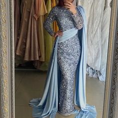 a woman taking a selfie in front of a mirror wearing a long blue dress