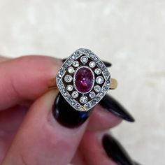 This antique ring was handcrafted during the Edwardian era and features a bezel-set 0.75ct sugarloaf cut natural ruby. The ruby is surrounded by a halo of single cut diamonds, followed by a second halo of rose cut diamonds. This ring is platinum on 18k yellow gold and decorated with fine milgrain. Circa 1905. ✦ GEMSTONE SPECIFICATIONS: Gemstone: Ruby Gemstone Weight: 0.75 Carats Gemstone Cut: Sugarloaf Cut ✦ ENGAGEMENT RING SPECIFICATIONS: Material: Platinum on 18k Yellow Gold Stones: Diamond, R Edwardian Ruby Ring, Oval Multi-stone Emerald Ring In Platinum, Art Deco Ruby Ring With Diamond Details, Platinum Ruby Ring With 17 Jewels, Pear-shaped Ruby Rings With Rose Cut Diamonds, Fine Jewelry Diamond Amethyst Ring With Halo Setting, Hallmarked Oval Ruby Ring In Art Deco Style, Heirloom Oval Diamond Ruby Ring, Art Deco Oval Multi-stone Sapphire Ring