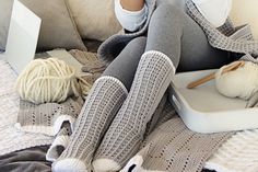 a woman sitting on a couch with her feet up in the air while knitting and crocheting