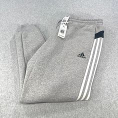 Elevate your activewear game with these stylish Adidas Multi Sport Jogger Pants in Men’s Size 2XL. Designed with a comfortable elastic waist and easy-care fabric, these pants are perfect for any season and any activity, whether you’re hitting the gym or going for a run outside. With water absorbent properties, these pants will keep you dry and comfortable during your workout. The gray color and white striped design, featuring the Adidas logo, make these pants a fashionable choice for any sports enthusiast. Featuring multiple pockets, these pants are both practical and stylish. Active Wear Pants, Pants Men, The Gray, Mens Activewear, Adidas Logo, Stripes Design, Jogger Pants, Grey And White, Mens Pants