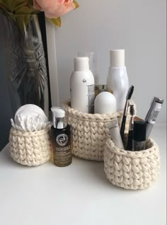 a white table topped with lots of beauty products and a vase filled with pink flowers