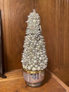 a small white christmas tree sitting on top of a wooden table