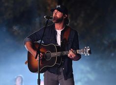 a man holding a guitar and singing into a microphone