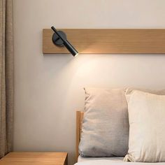 a light that is on the side of a wall next to a bed with pillows