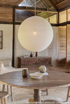 a round wooden table sitting in front of a white ball hanging over it's head