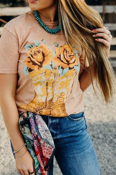 Saddle up in style with our Boots & Roses Tee! Made from soft 100% cotton fabric, this western tshirt features a playful cowboy boots and roses graphic, perfect for any cowgirl. The coral mineral wash adds a unique touch to this short sleeve tee. Haylee is wearing size small paired with The Carter Jeans, the Coyote Knox Sandals and Vintage Feedsack Wild Rag Country Style Tops For Western-themed Spring Events, Country Style T-shirt For Spring Events, Casual Spring T-shirt For Country Events, Spring Graphic Tee For Western-themed Events, Western Style Tops For Western-themed Spring Events, Spring Western Style Tops For Western-themed Events, Graphic Tee For Western-themed Spring Events, Spring Country Style T-shirt For Country Events, Country Style T-shirt For Western-themed Summer Events