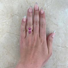 This gorgeous ring features a 1.92 carat oval-cut pink tourmaline ring that is set in prongs. Flanking either side of the stone are two oval-cut diamonds weighing approximately 0.11 carats. Additional prong-set rubies and spinel form a halo around the center stone. The total weight of the spinel is approximately 0.11 carats and the total weight of the rubies is approximately 0.25 carats. This ring is handcrafted in 18k yellow gold.
The measurements of the center tourmaline are 9.34mm x 6.53mm x Gia Certified Oval Pink Diamond Ring, Oval Pink Gia Certified Diamond Ring, Gia Certified Oval Pink Ruby Ring, Pink Oval Diamond Ring With Accent Stones, Oval Pink Diamond Ring With Accent Stones, Pink Cushion Cut Morganite Jewelry, Pink Tourmaline Jewelry With Accent Stones, Pink Oval Fine Jewelry, Gia Certified Emerald Cut Pink Jewelry