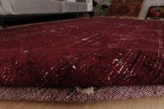 a close up of a red rug on a wooden floor