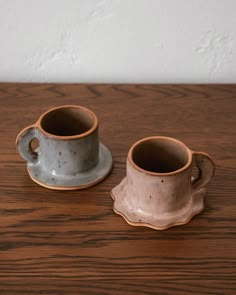 two coffee cups sitting on top of a wooden table